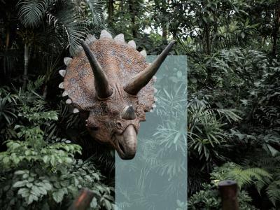 En hornet dinosaur stikker hovedet frem mellem tæt, grøn jungle.