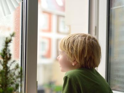 Dreng kigger ud af vinduer på regnen